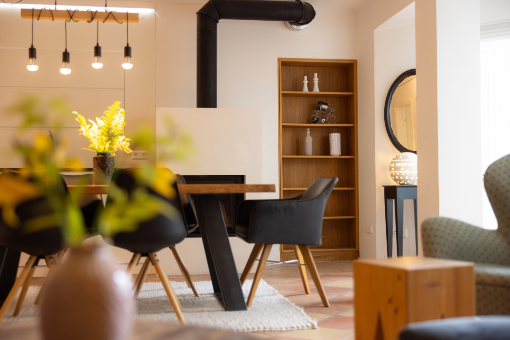 Ferienwohnung mit Hotel Service im Hotel Annelies Blick vom Sofa ins helle Esszimmer mit Holztisch und Kamin – Ferienwohnung im Hotel Annelies.