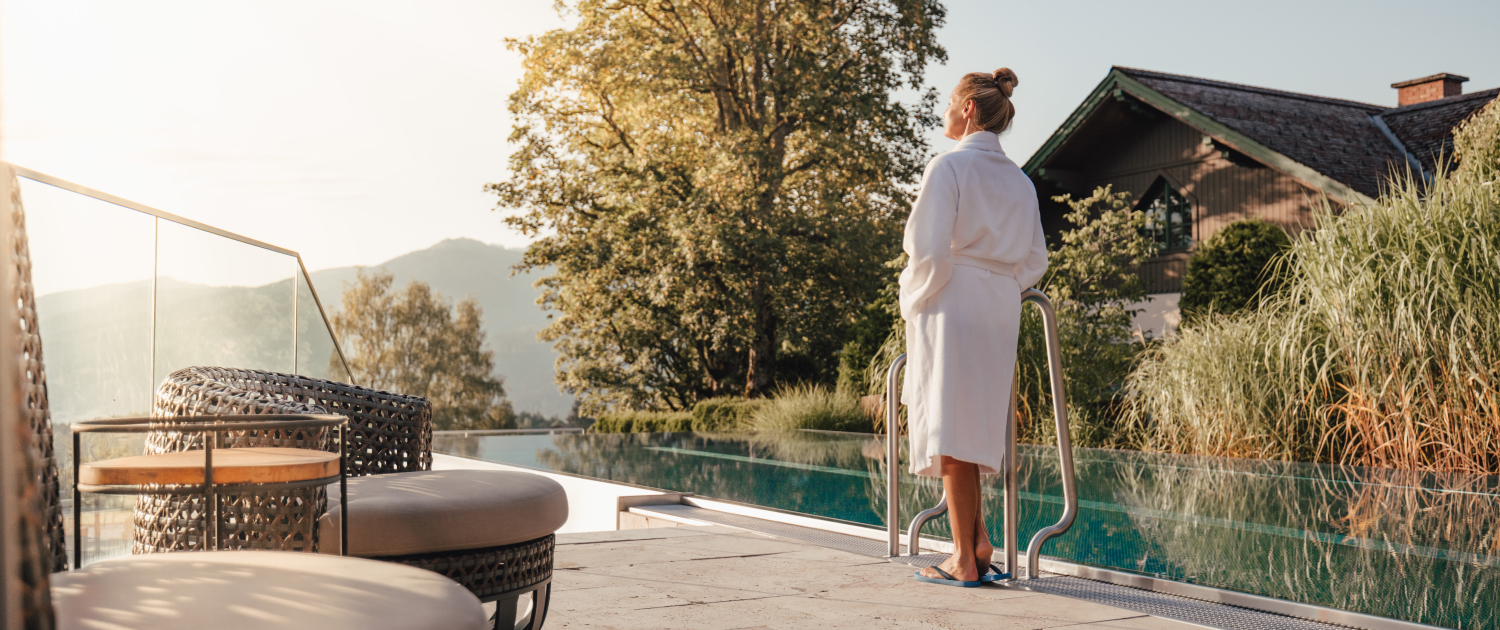 Frau im Bademantel stehend vor dem Infinity Pool des Hotels Annelies