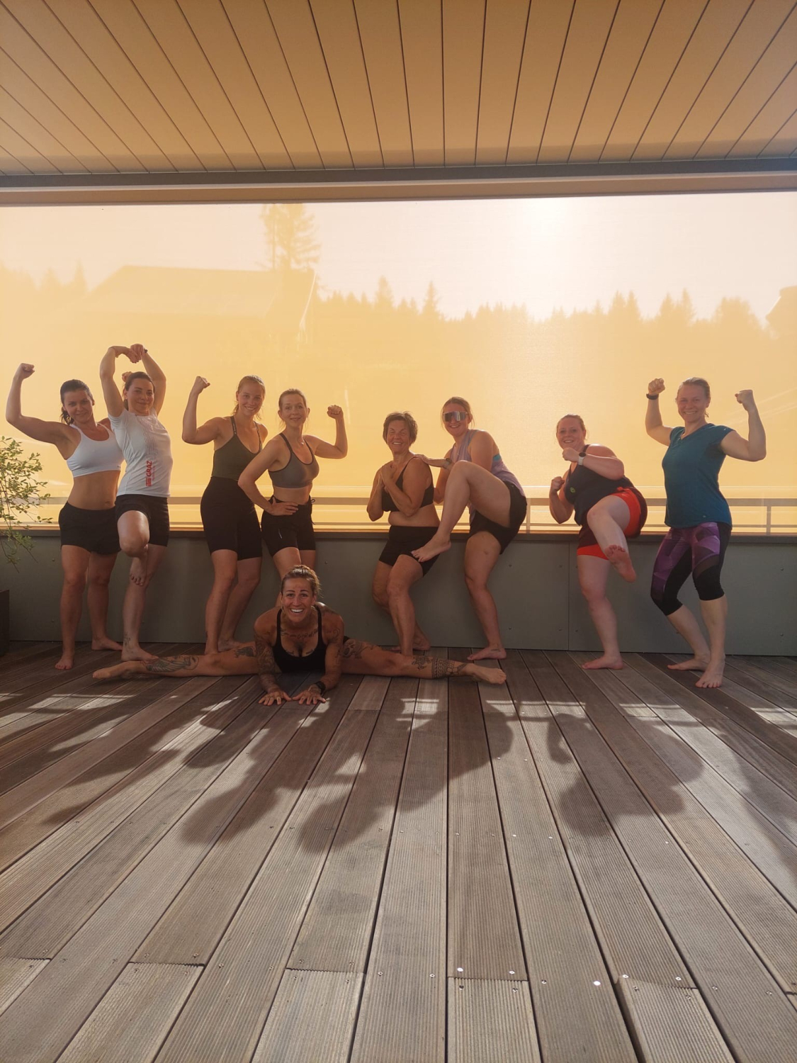 Zusehen sind neun Frauen in Sportkleidung auf einem Fitness Camp, die gemeinsam ein Gruppenfoto machen.