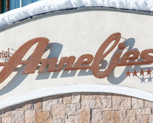 Auf dem Bild ist ein Hotelschild zu sehen. Darauf steht in großer Schrift „Hotel Annelies“ und daneben sind vier Sterne abgebildet. Das Schild ist an einer Hauswand montiert.