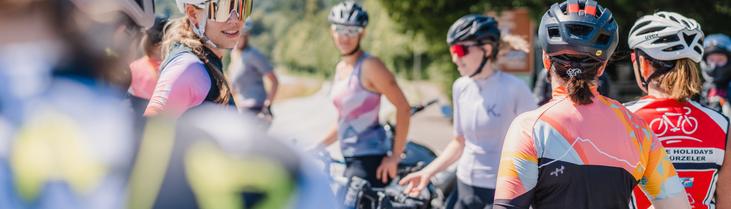 Das Bild zeigt eine Gruppe von Radfahrerinen, die am Straßenrand eine Pause machen.