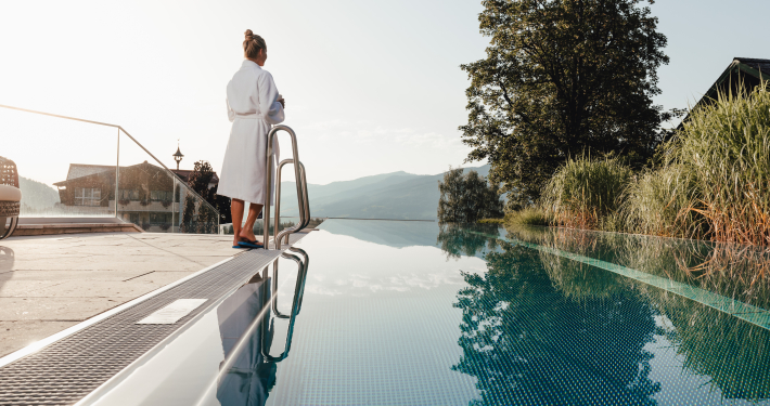 Infinity Pool des Hotel Annelies Eine Frau im Bademantel steht an einem Infinity Pool und genießt die Ausicht.