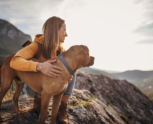 Woman hiker with her dog on mountain peak