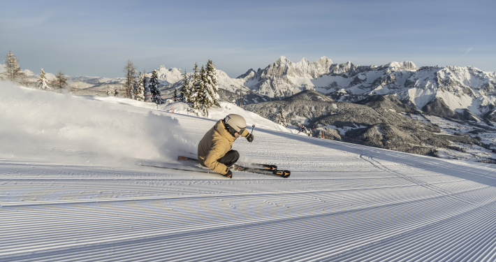 Skifahren Reiteralm Mirja Geh Eine Skifahrerin fährt auf einer Piste. im Hintergrund ist eine beeindruckende Bergkulisse zu sehen.