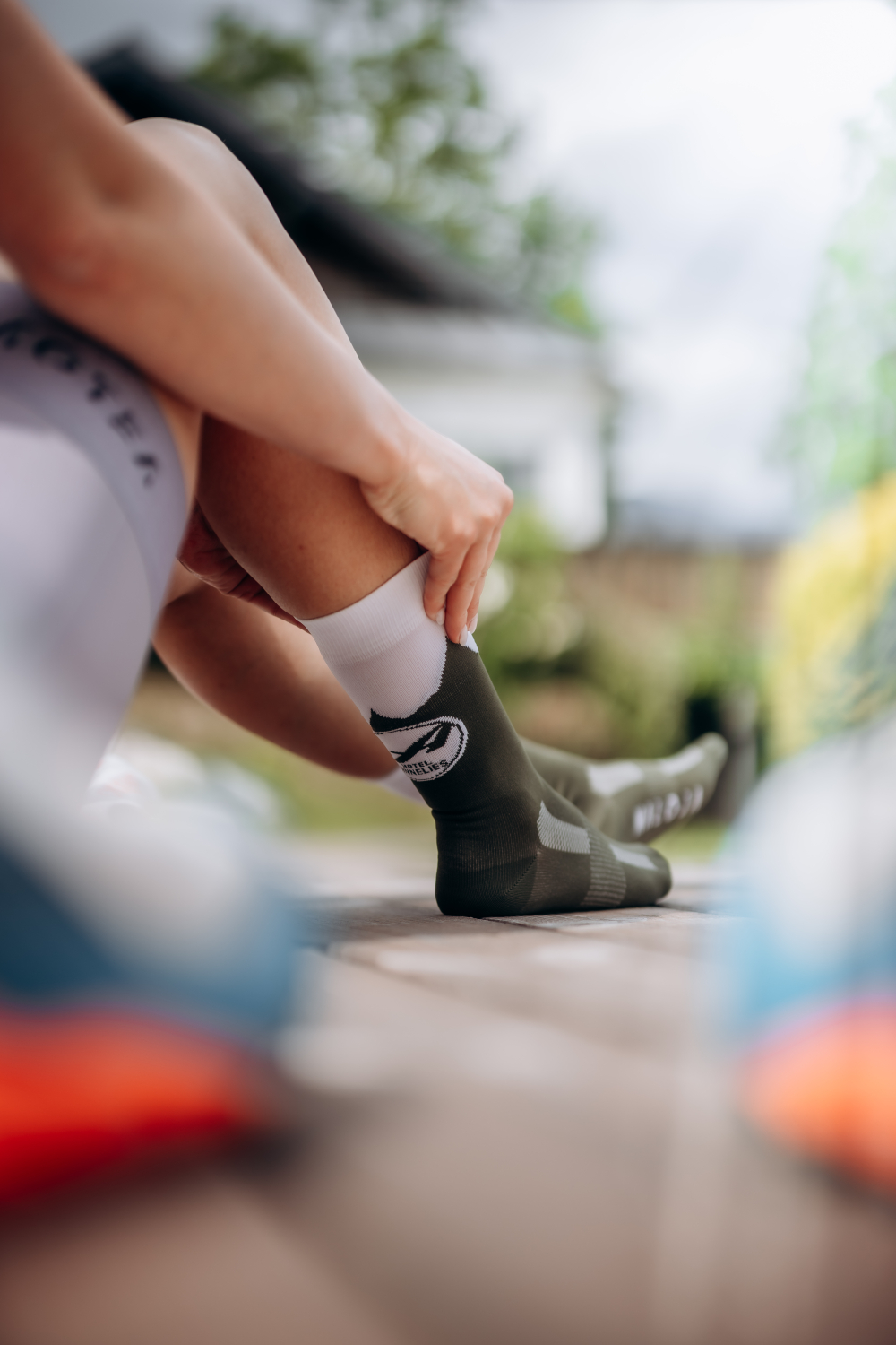 Eine Frau, die nicht vollkommen zu erkennen ist, zieht sich Socken mit dem Werbelogo von Hotel Annelies an.