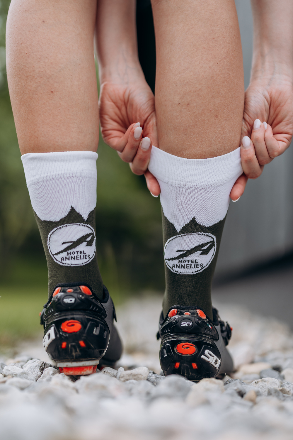Eine Person, dessen Beine man nur sieht, richtet sich ihre Socken, welche das Logo von Hotel Annelies tragen.